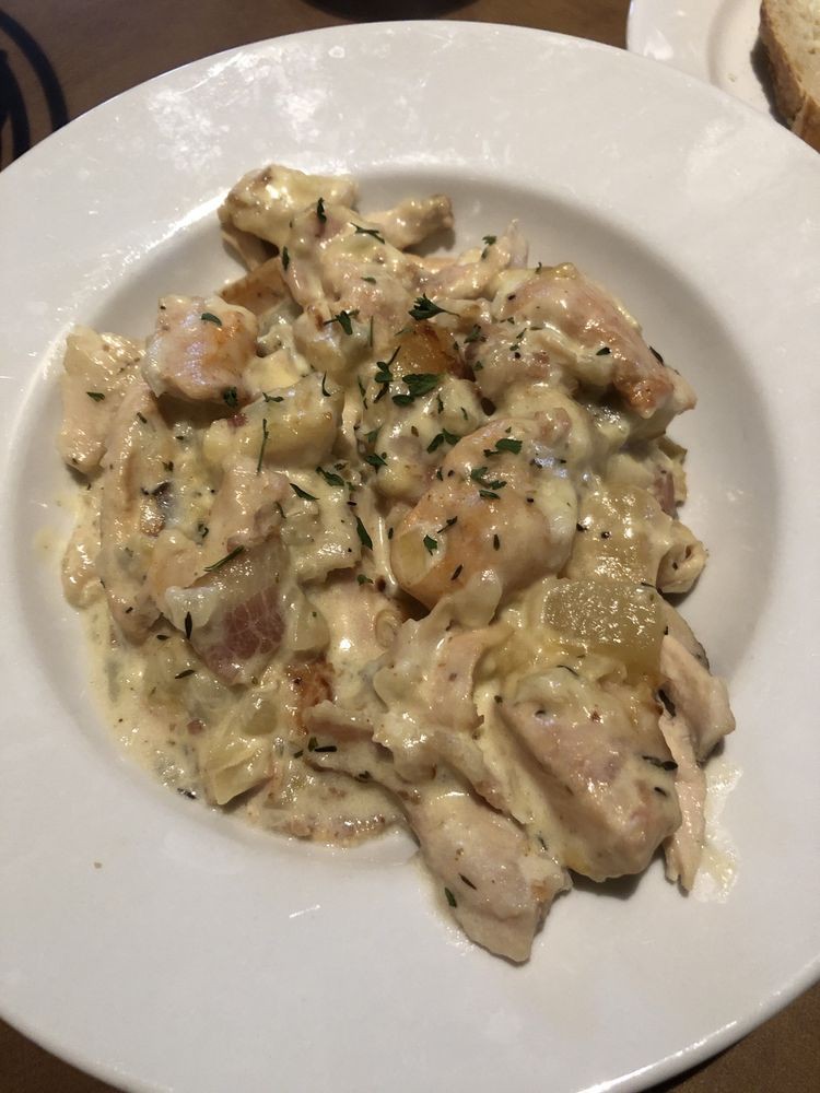 A plate of creamy chicken pasta garnished with herbs.