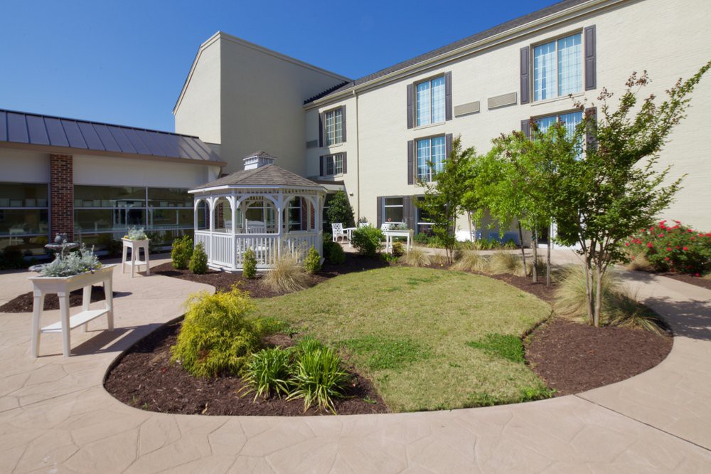 A well-maintained garden with a gazebo outside a modern building.