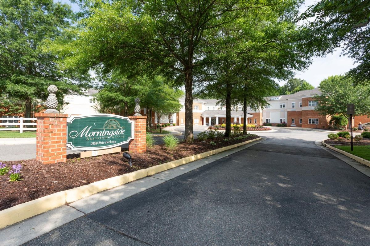 The entrance to a residential complex with a sign and well-maintained landscaping.