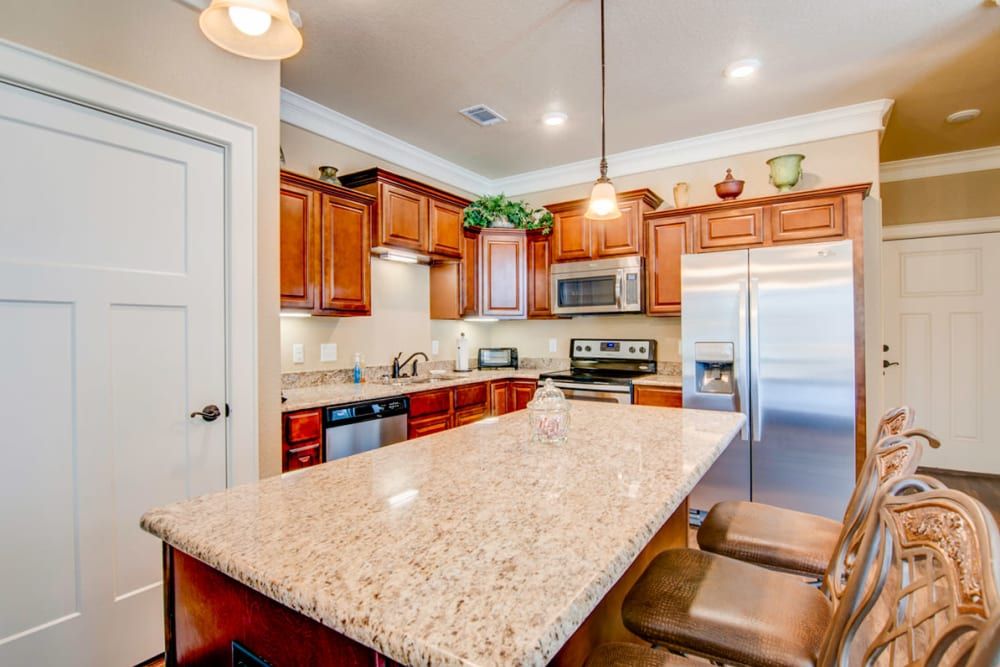 A modern kitchen with granite countertops, wood cabinets, and stainless steel appliances.