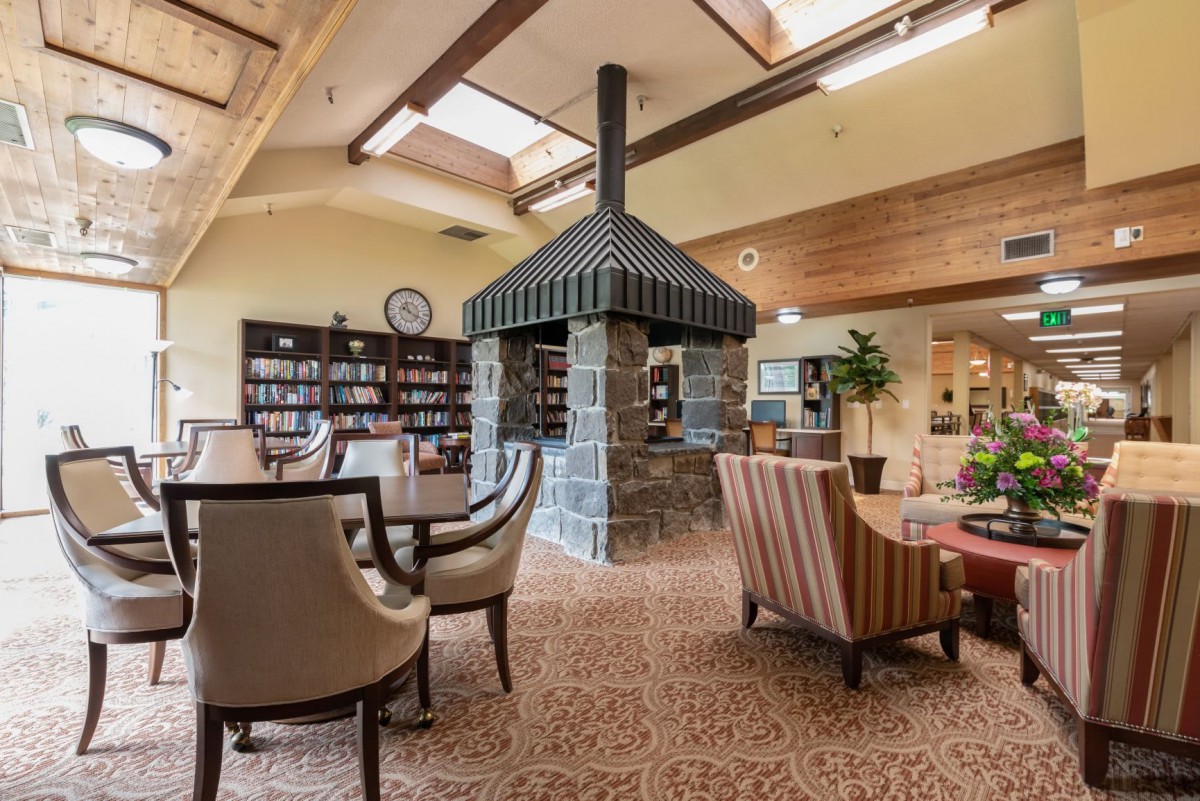 A cozy interior space featuring a seating area with a central fireplace and surrounding bookshelves.