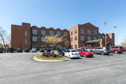 A modern brick building with a parking lot filled with various vehicles under a clear blue sky.