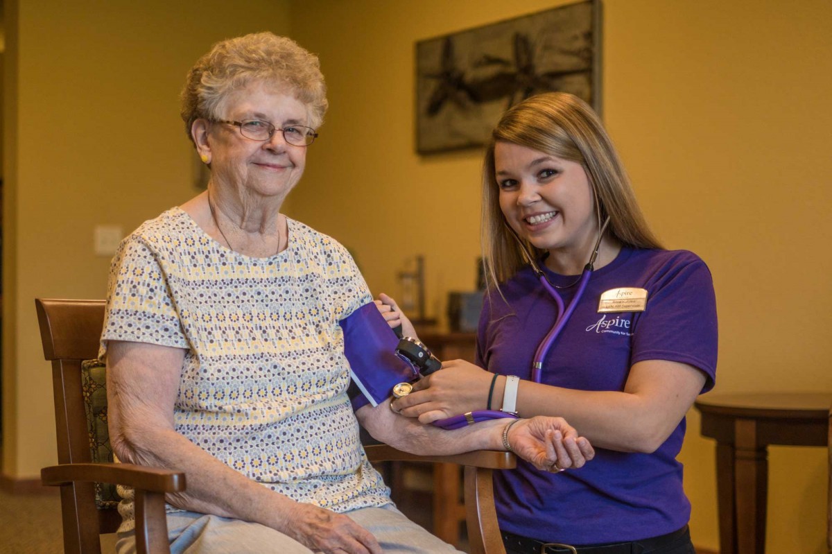 A nurse assists an elderly woman by taking her blood pressure.