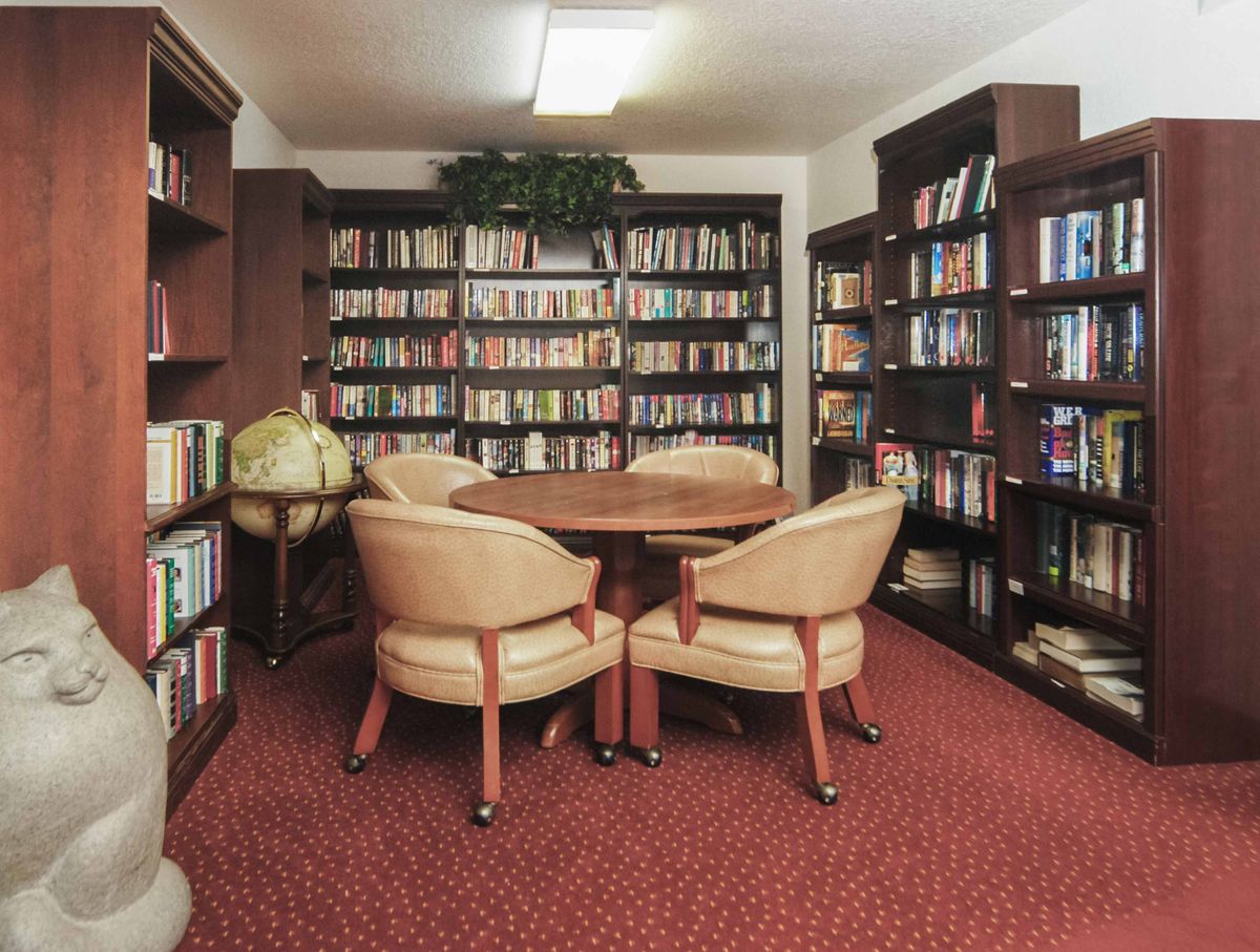 A cozy library corner with bookshelves filled with books and a reading area featuring chairs and a table.