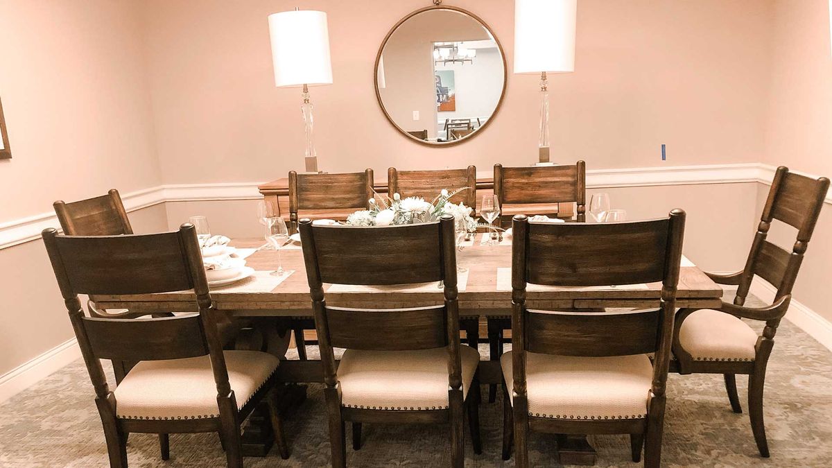 A beautifully set dining area with wooden chairs, a large mirror, and soft lighting.
