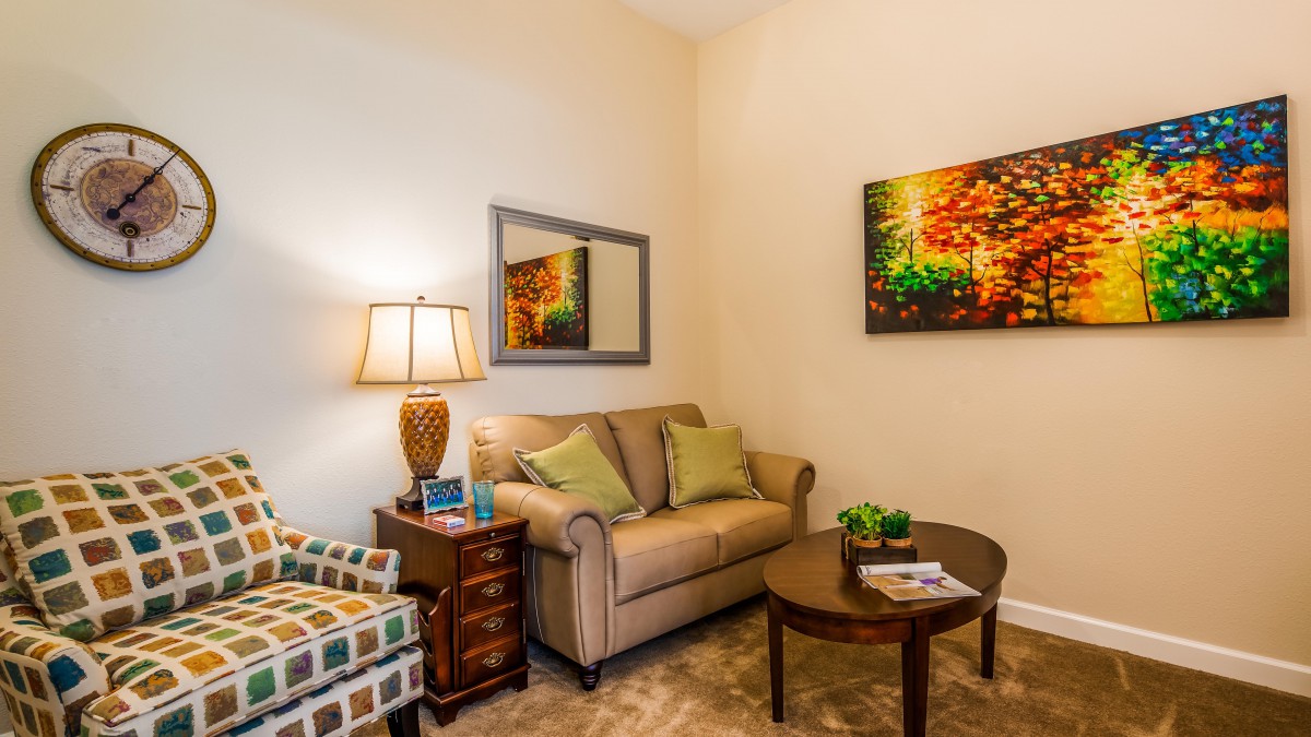 A cozy living room with a sofa, armchair, and colorful artwork.