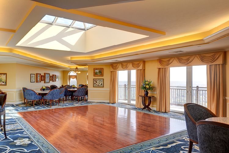 A luxurious living room with wooden floors, elegant dining area, and a skylight providing ample natural light.