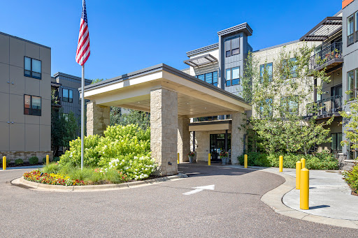 The welcoming entrance of a modern hotel with well-kept landscaping and an American flag prominently displayed.