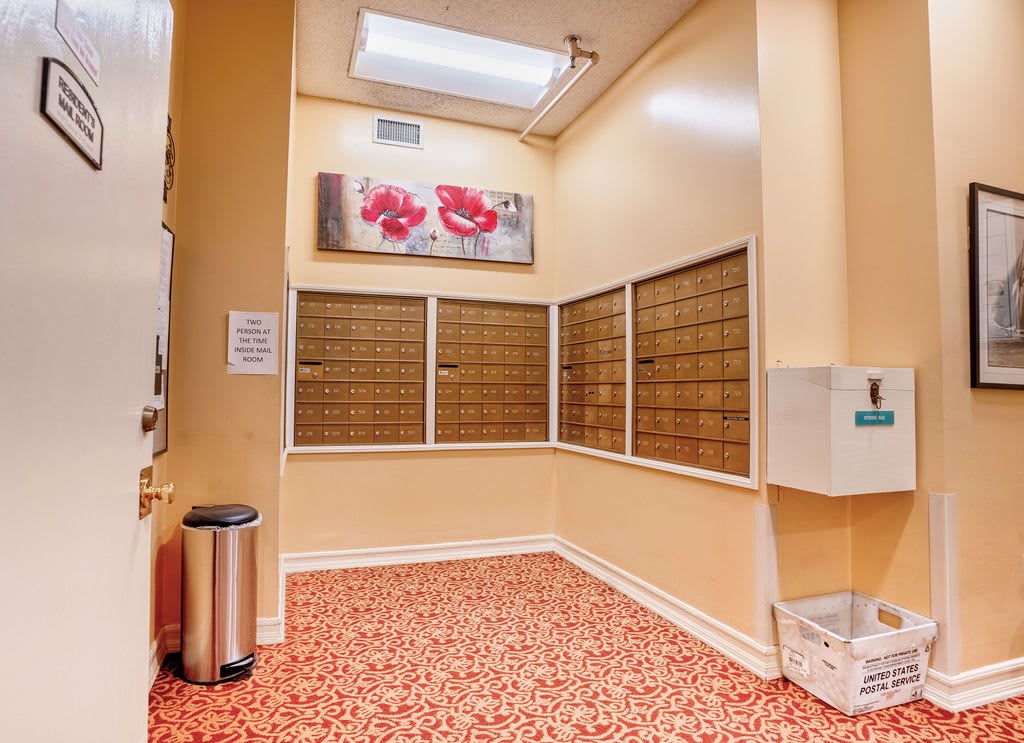A neatly organized mail room with multiple mailboxes and decorative artwork on the wall.