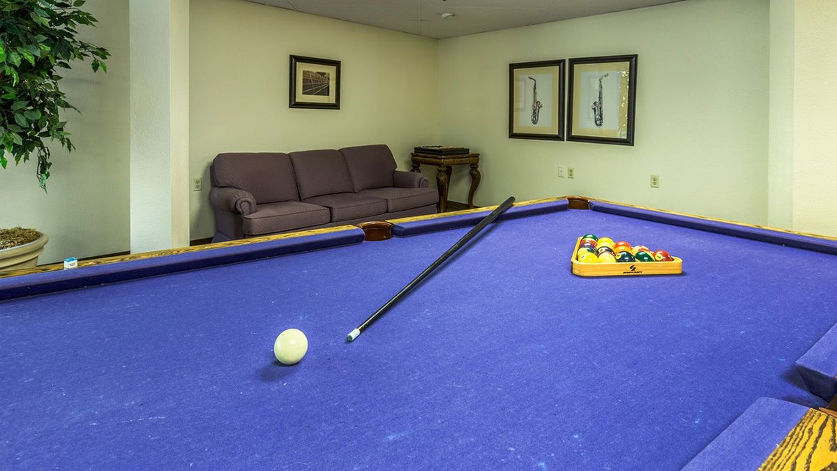 A recreation room featuring a billiards table with a cue stick and balls ready for play.