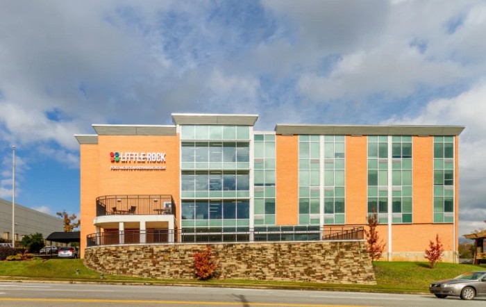 A modern building with glass windows and a brick exterior under a cloudy sky.