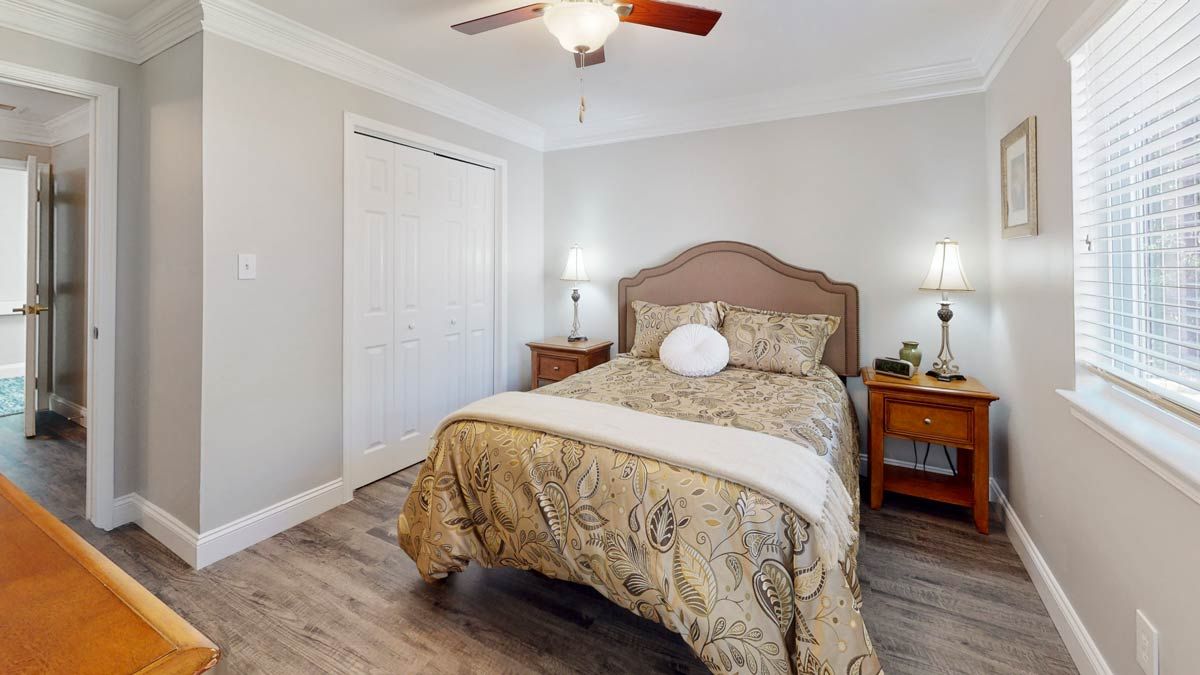 A cozy bedroom with a ceiling fan, bed, and nightstands.