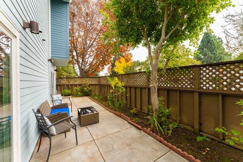 A cozy patio area with seating and a fenced garden.