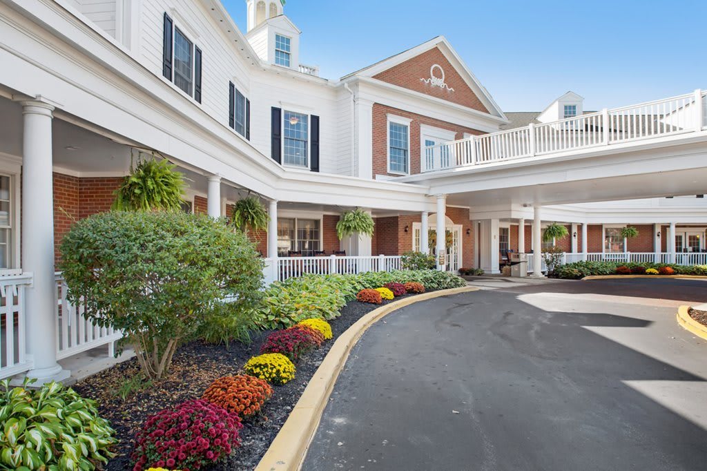 A beautifully landscaped building exterior with a driveway and vibrant flowers.