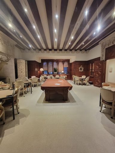 A spacious modern dining room featuring a large wooden table surrounded by elegant chairs, illuminated by soft lighting.