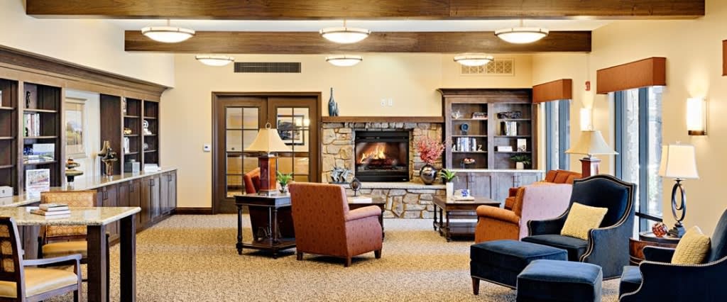 A cozy lounge with a fireplace, comfortable seating, and a bookshelf.