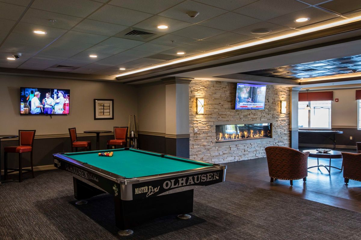 A cozy recreation room featuring a pool table, televisions, and a modern fireplace with comfortable seating.