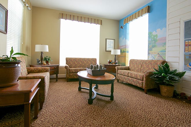 A cozy living room with matching sofas and a coffee table, illuminated by natural light from large windows.