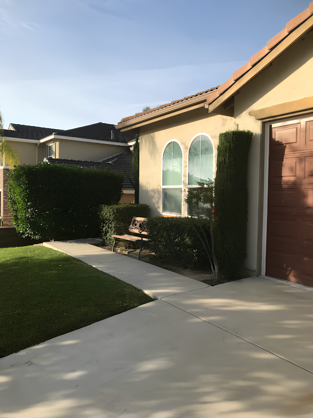 A sunny view of a house with a well-maintained lawn and pathway.