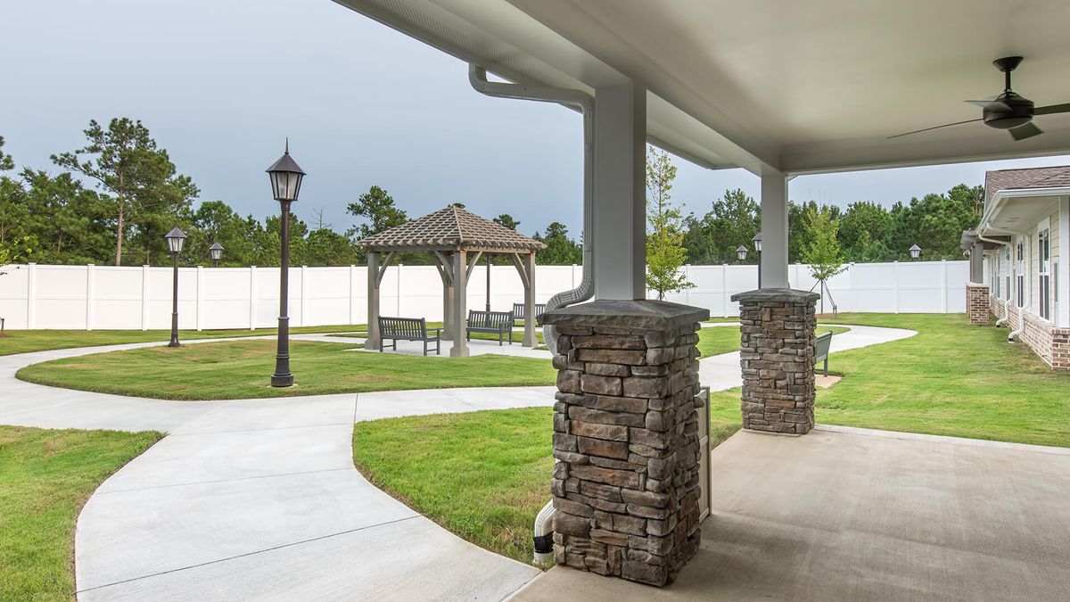 A well-maintained garden with a covered patio, stone columns, and a gazebo.
