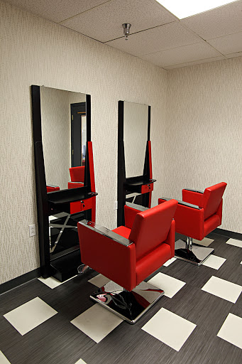A modern hair salon featuring stylish red chairs and large mirrors.