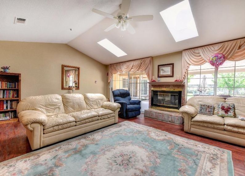 A cozy living room with a sofa set, fireplace, and skylights.