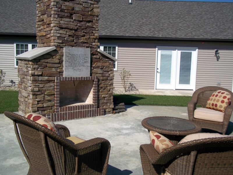A cozy backyard patio featuring a stone fireplace and comfortable seating.