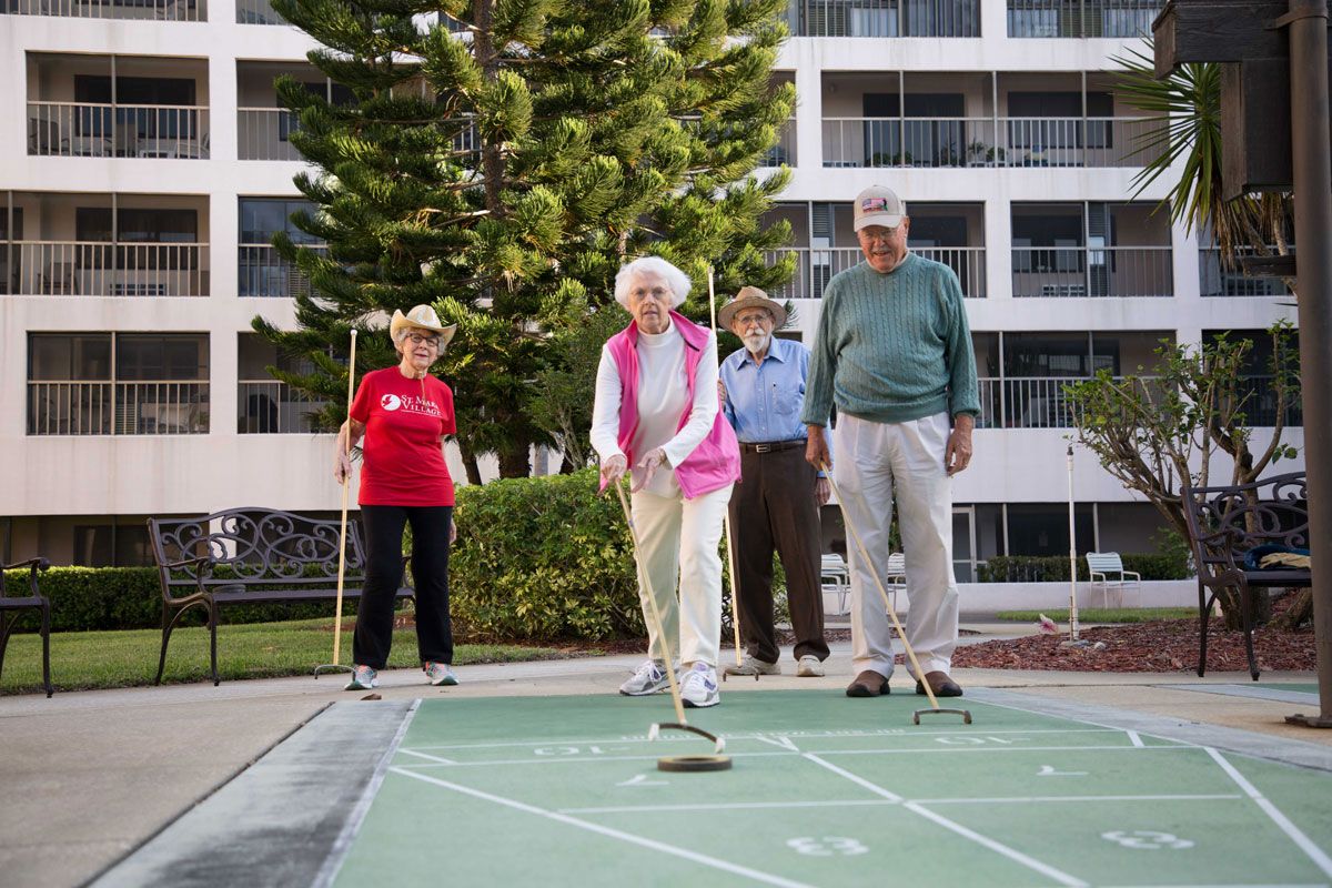 A group of seniors playing shuffleboard outdoors, enjoying recreational activities in a community setting.