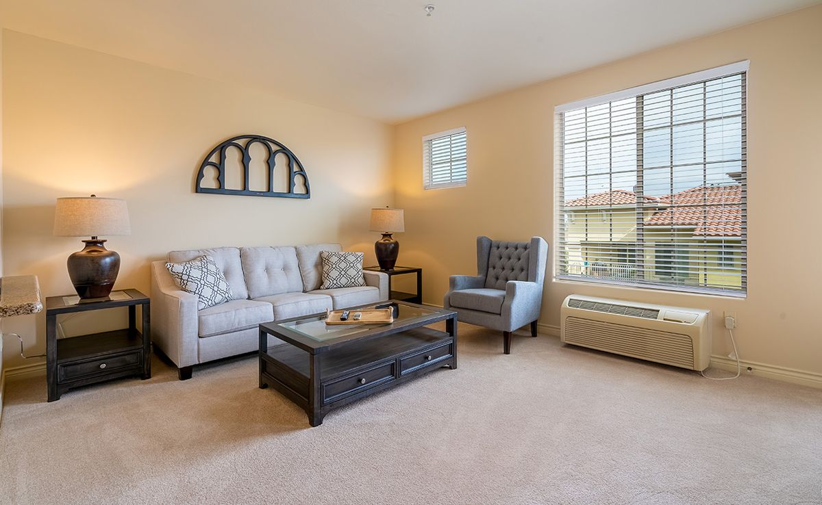 A cozy living room with a sofa, armchair, and coffee table under warm lighting.