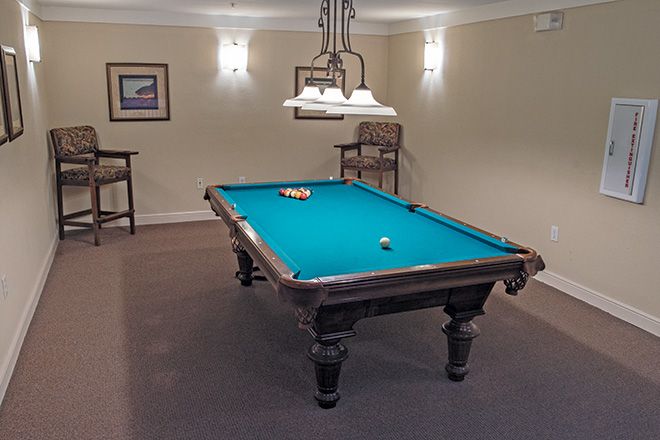 A cozy game room featuring a billiards table under warm lighting.