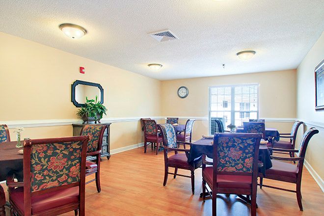 A cozy dining room with floral upholstered chairs and round tables under soft lighting.