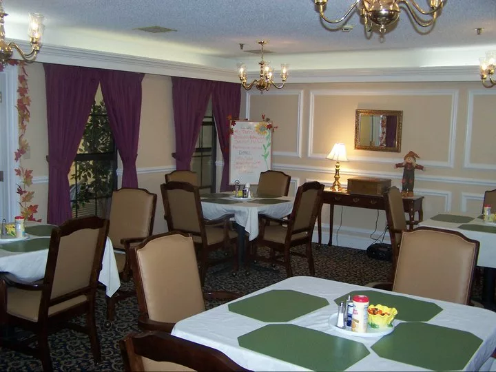 An elegantly decorated dining room with a table and chairs, featuring a chandelier and purple curtains.