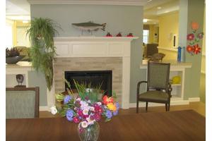 A cozy living room with a fireplace and a vibrant flower arrangement.