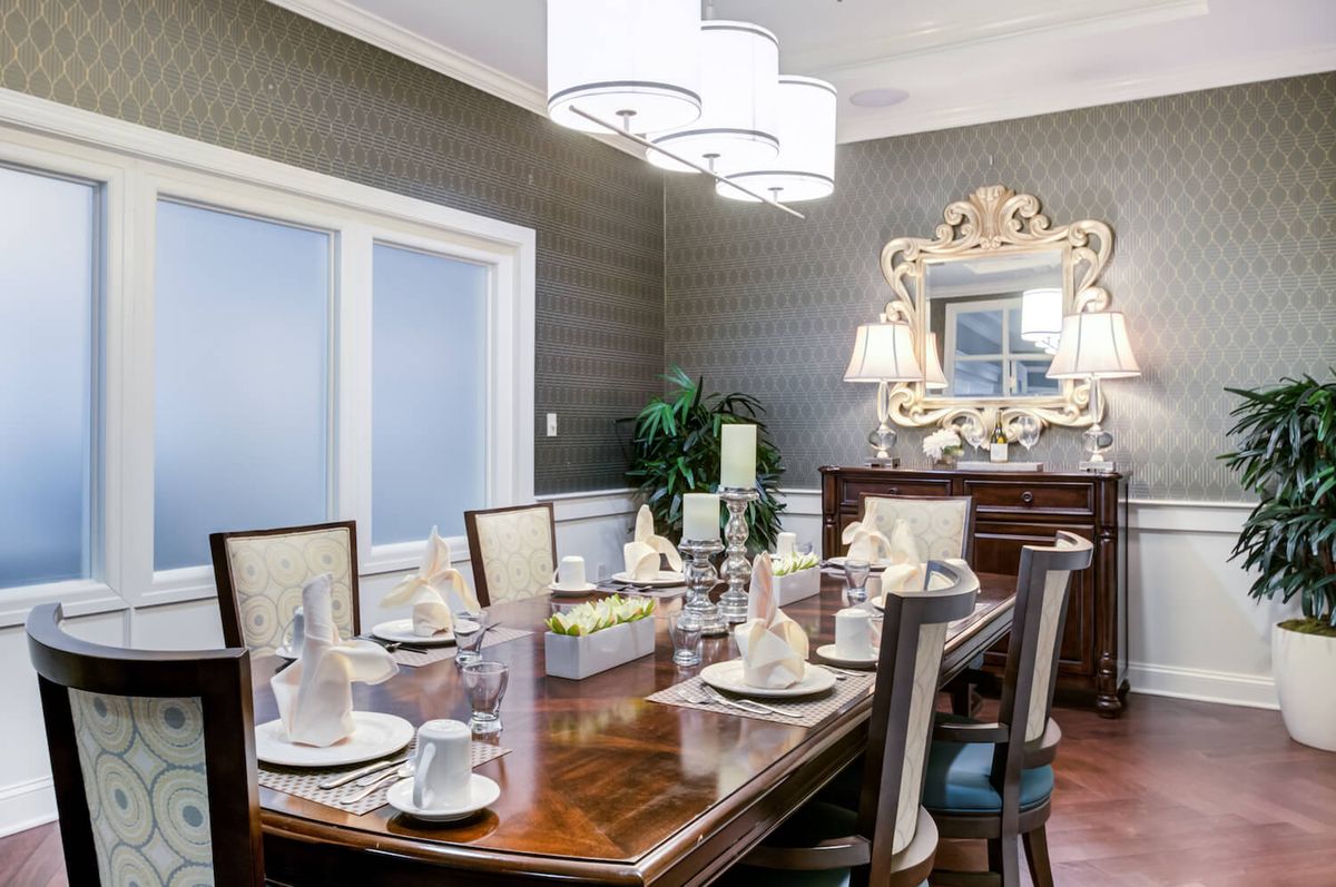 An elegantly designed dining room with a beautifully set table, featuring stylish lighting and a decorative mirror.