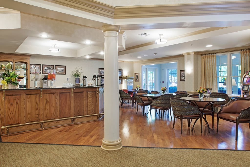 A cozy dining area with several tables and chairs, featuring a wooden floor and elegant decor.