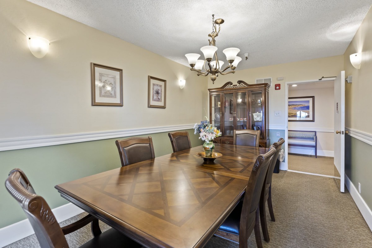 A well-decorated dining room featuring a large wooden table, cushioned chairs, a china cabinet, and an elegant chandelier.