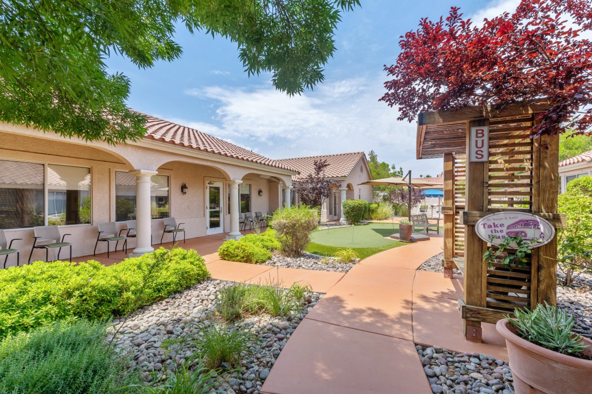 A beautiful residential property featuring a landscaped garden with trees, a walkway, and patio areas.
