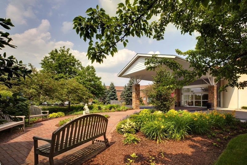 A peaceful garden area with a bench and lush greenery in front of a building.