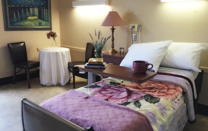 A cozy hospital room with a bed, nightstand, and a floral blanket.