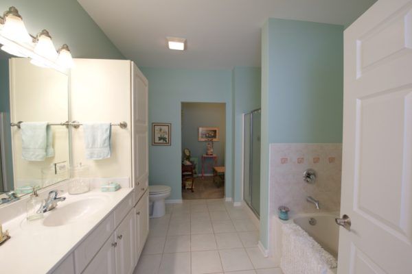 A modern bathroom featuring a bathtub, shower, and double sink with mirrors.