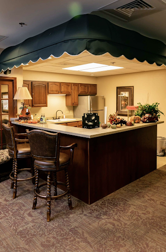 A cozy kitchen area featuring a central island with bar stools, wooden cabinetry, and decorative elements.
