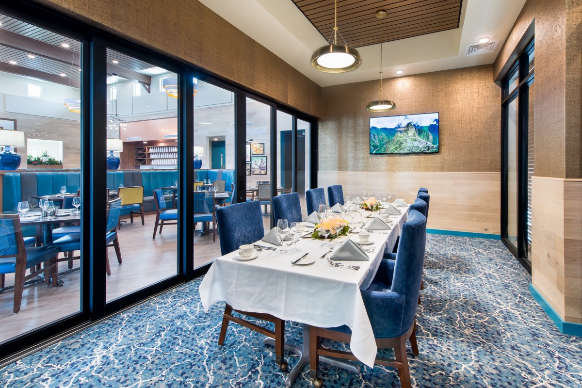 An elegantly set dining table in a restaurant with blue chairs and stylish decor.