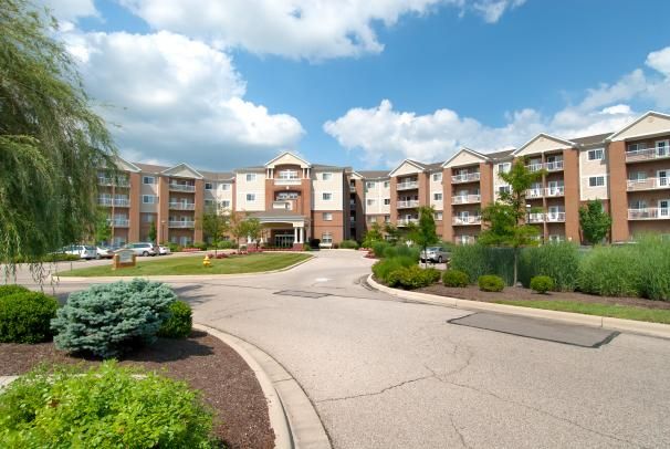 A modern apartment complex with well-maintained landscaping under a partly cloudy sky.