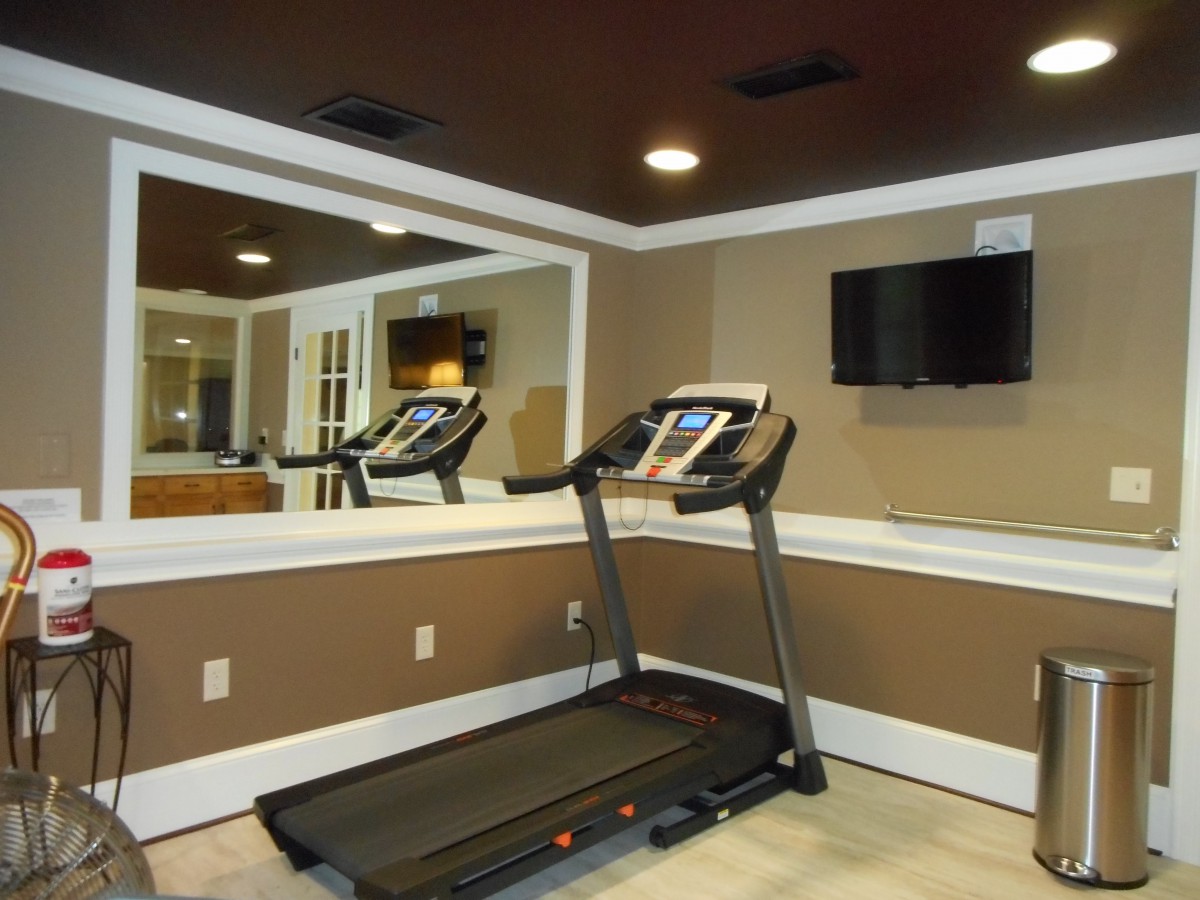 A home gym with a treadmill and mirrored walls.