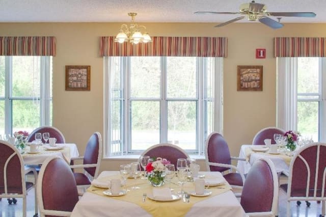A bright dining room with elegantly set tables and a large window.