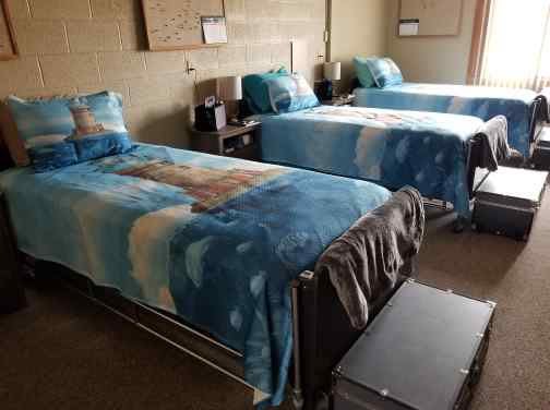 A hospital room featuring two twin beds with blue bedding.