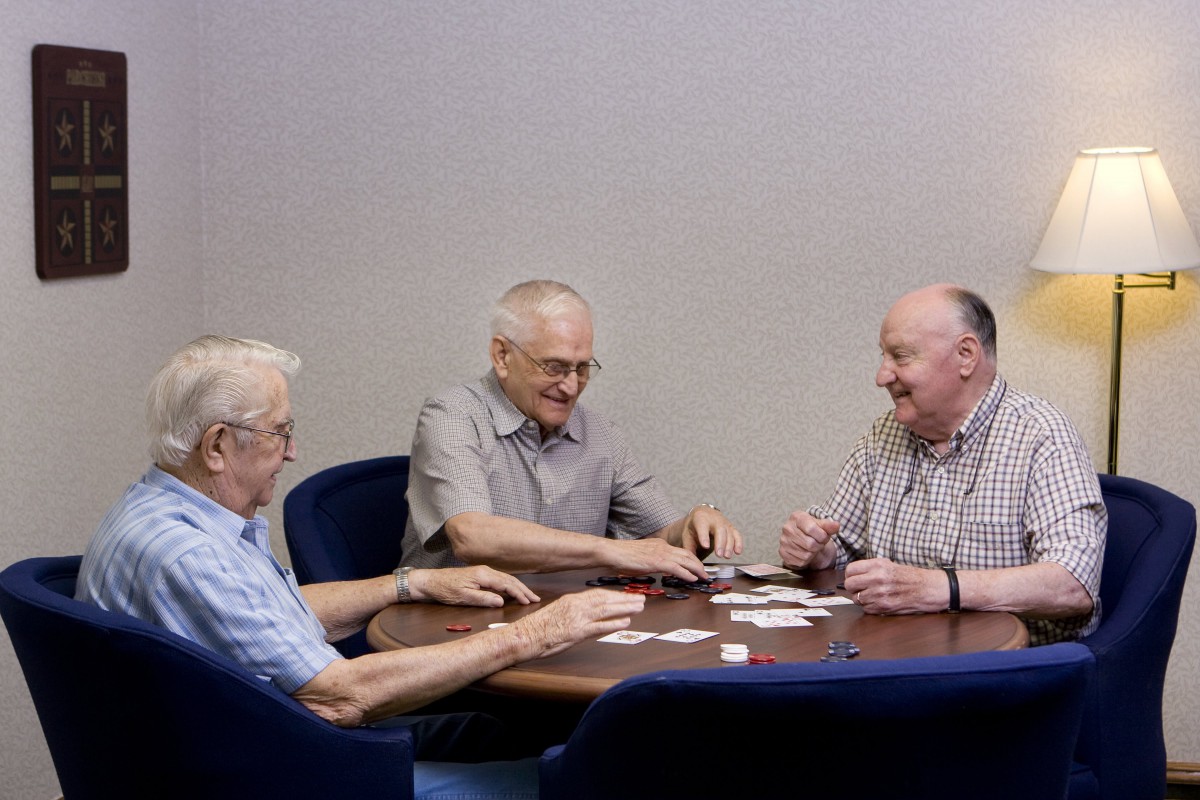 Three elderly men enjoying a card game at a table.