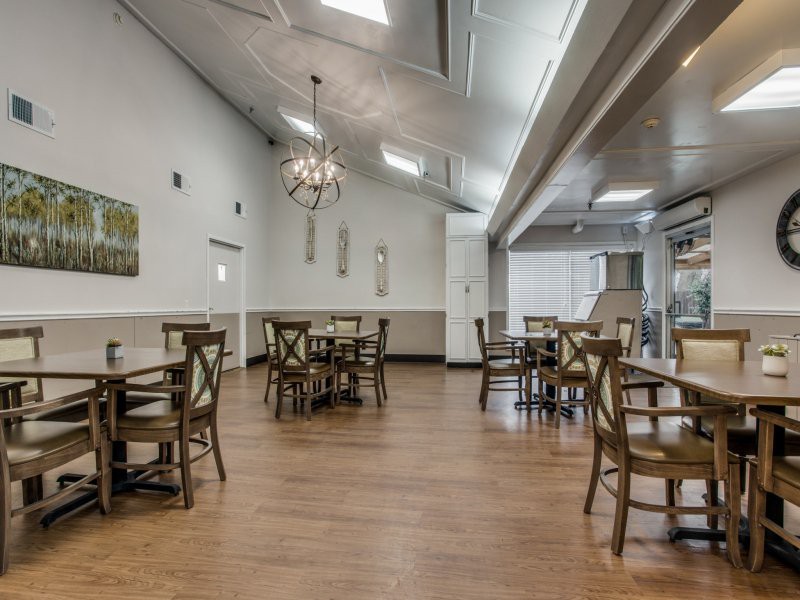 An empty restaurant interior with wooden floors, tables, and chairs.