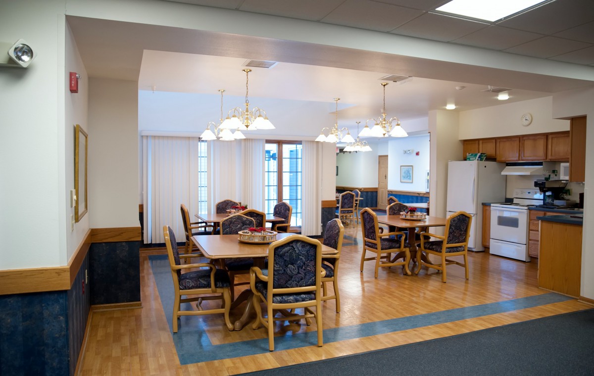 A spacious dining area with wooden tables and chairs, illuminated by overhead lighting.