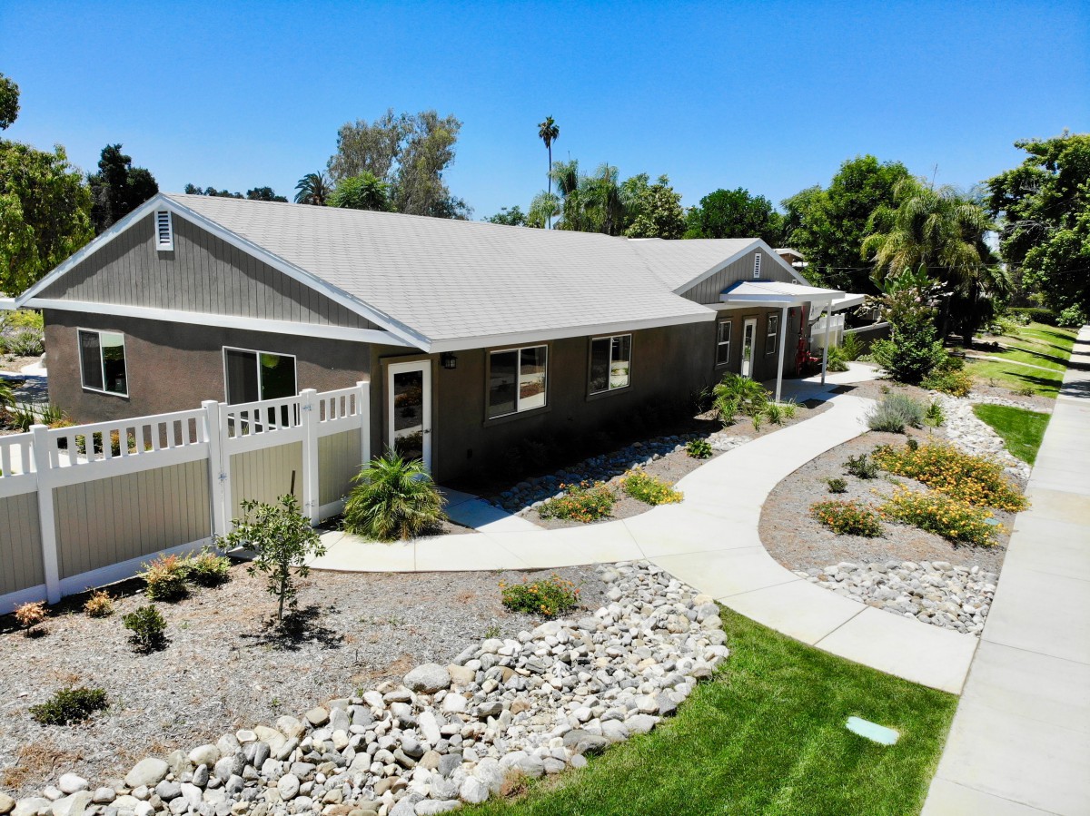 A single-story house with a landscaped garden and a curving pathway on a sunny day.
